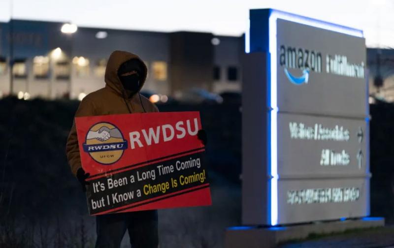 person with pro-union sign standing outside of an Amazon warehouse